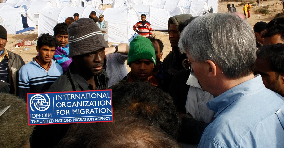 Bild Flüchtlingscamp (Libyen): Department for International Development/Kate Joseph via Flickr [CC BY 2.0] (Bild zugeschnitten) / IOM Logo: YvonneIOM via Wikimedia Commons [CC BY-SA 4.0] (umrahmt) / Collage: Die Tagesstimme. 
