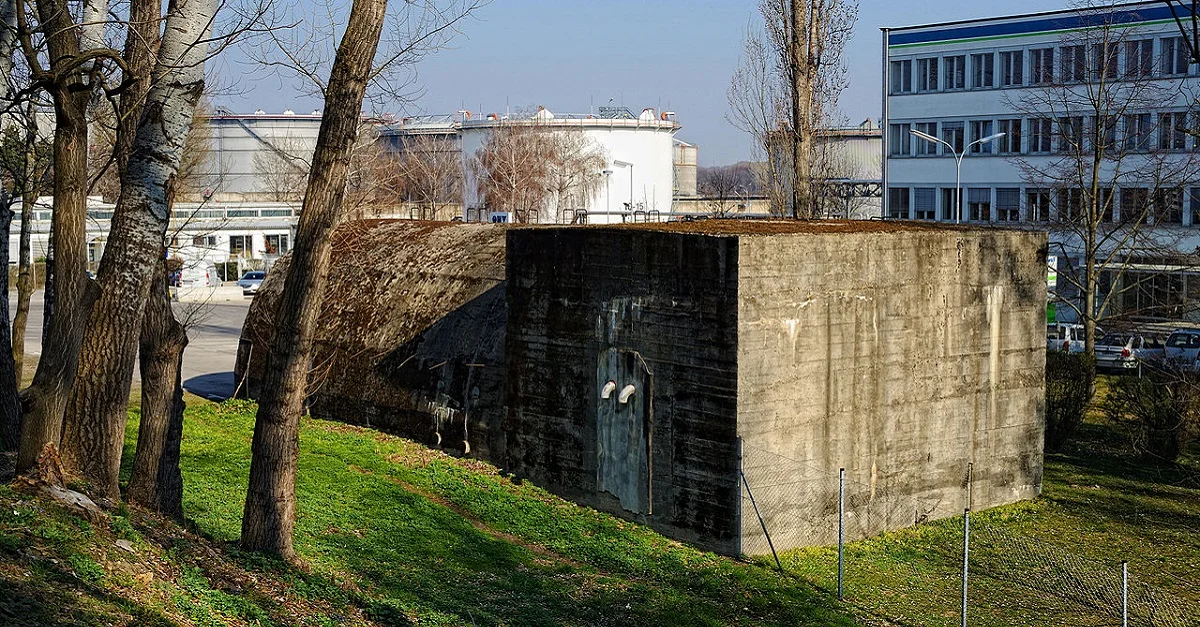 Neben der grünen Parteijugend beteiligten sich auch zwei gegenwärtige Mandatare der Partei an einer Sitzblockade vor dem OMV-Gelände in der Lobau. Symbolbild (Bunker auf dem OMV-Gelände in der Lobau + Bürogebäude): Linie29 via Wikimedia Commons [CC BY-SA 3.0] (Bild zugeschnitten)
