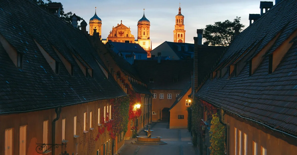 Bild: Die Fuggerei bei Nacht / Bild: Wolfgang B. Kleiner / context medien und verlag Augsburg, CC BY 3.0, via Wikimedia Commons (Bild zugeschnitten)